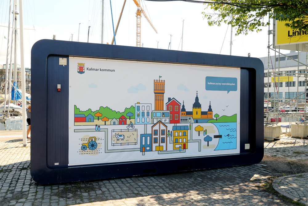 En informationshub med en stor illustration på väggen som visar ikoniska byggnader från Kalmar kommun, av Frida Hagman